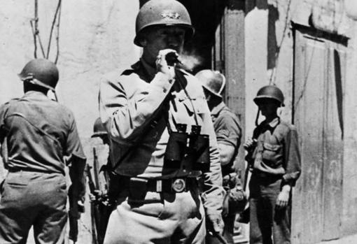 El teniente general Patton fuma un puro en una casa de Hela mientras observa el avance de las tropas norteamericanas
